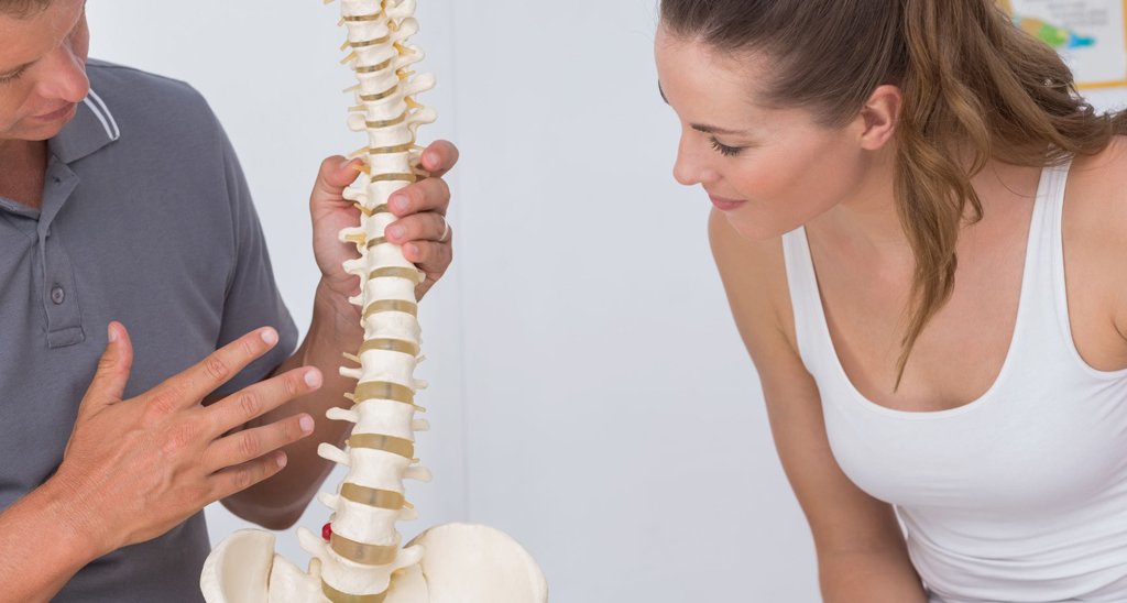 Exercise specialist showing a client a model of a spine